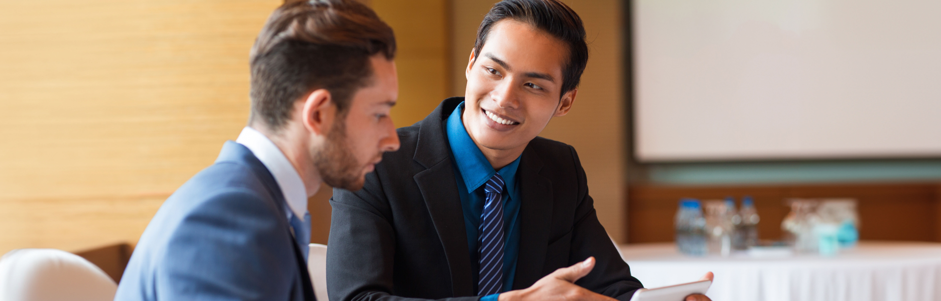 Closeup Two Smiling Coworkers Using Tablet Expanded